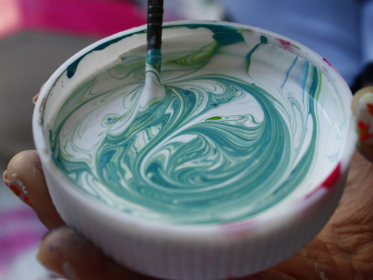 Pennello intinto nel colore verde e nel colore bianco mentre mescola le due tinte