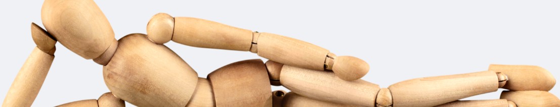 Immagine di un manichino in legno disteso a terra che sorregge la testa con il braccio destro