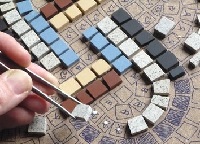 mano che realizza un mosaico disegnato su supporto di cartone
